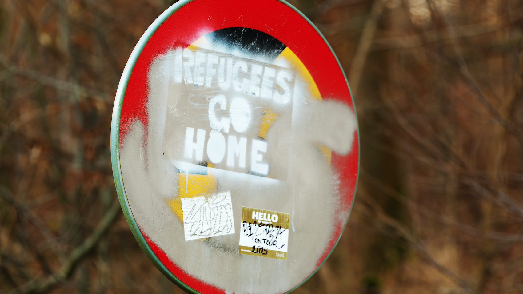 Racist and hateful message saying "Refugees Go Home", painted on a traffic sign with stickers and paint all over in Karlskrona, Sweden on January 13, 2016.