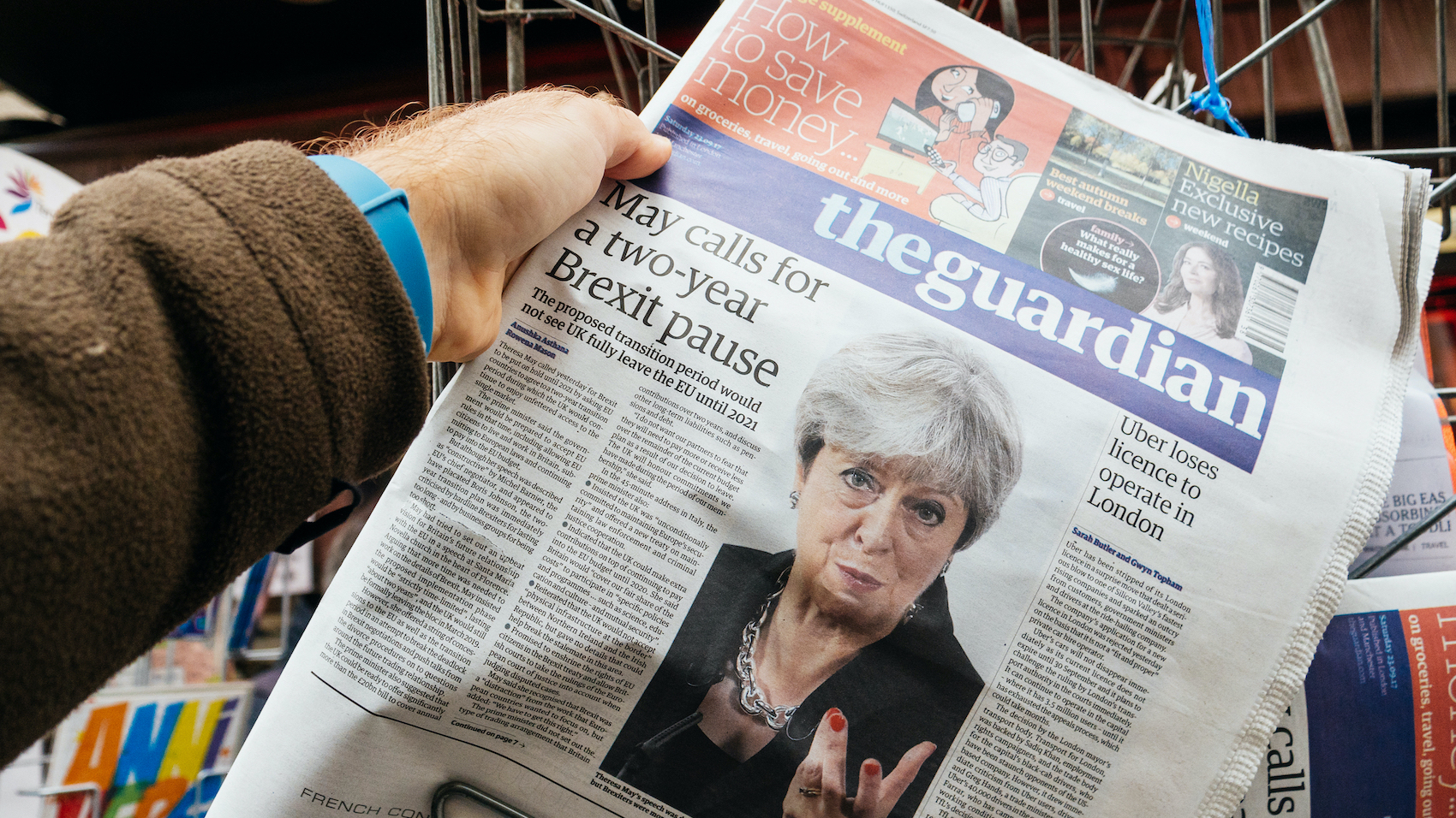 Man buying The Guardian newspaper from press kiosk with Braking news from Theresa May British Prime Minister "Brexit delayed two years" in Paris on September 25, 2017.