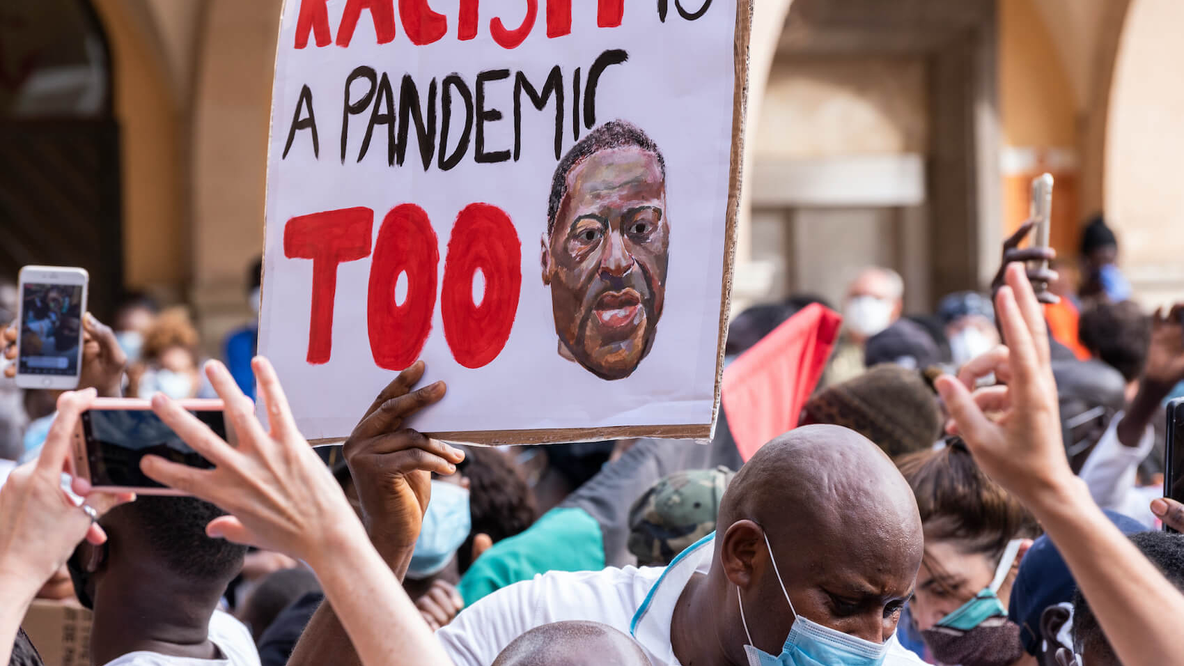 Man surrounded by crowd holding a banner with the message about racism in a peaceful protest against racism and US police brutality in Palma de Mallorca, Spain on June 07 2020.