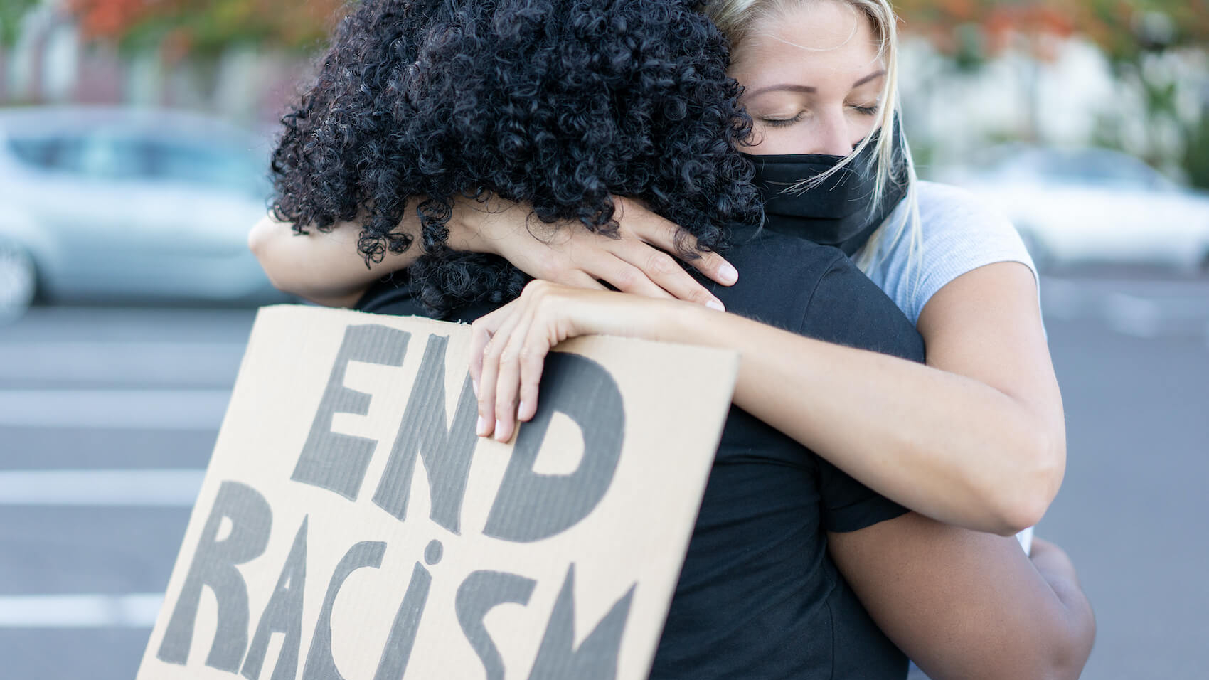 A young African woman hugging a white northern woman after a protest. Photo: Sabrina Bracher.