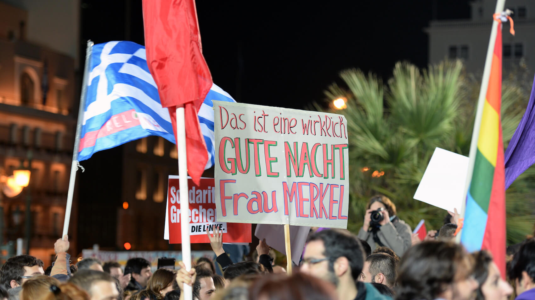 Supporters of Syriza left wing party with flags outside Athens University in Greece on January 25, 2015. The baner says:"This is really good night Mrs Merkel." Syriza, won general elections. Photo: Kostas Koutsaftikis.