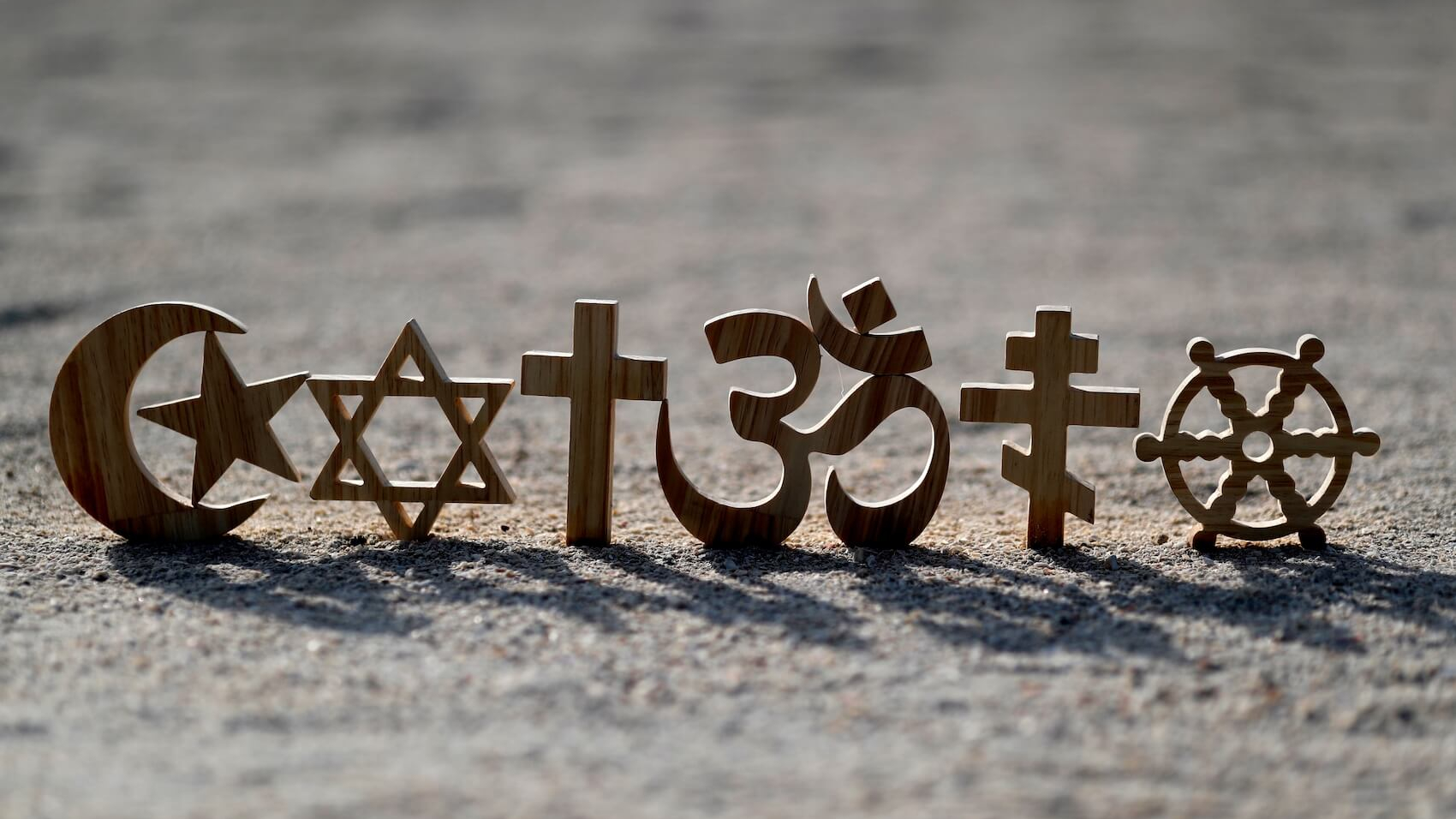 Religious symbols on sand: Christianity, Islam, Judaism, Orthodoxy Buddhism and Hinduism. Photo: Godong Photo.