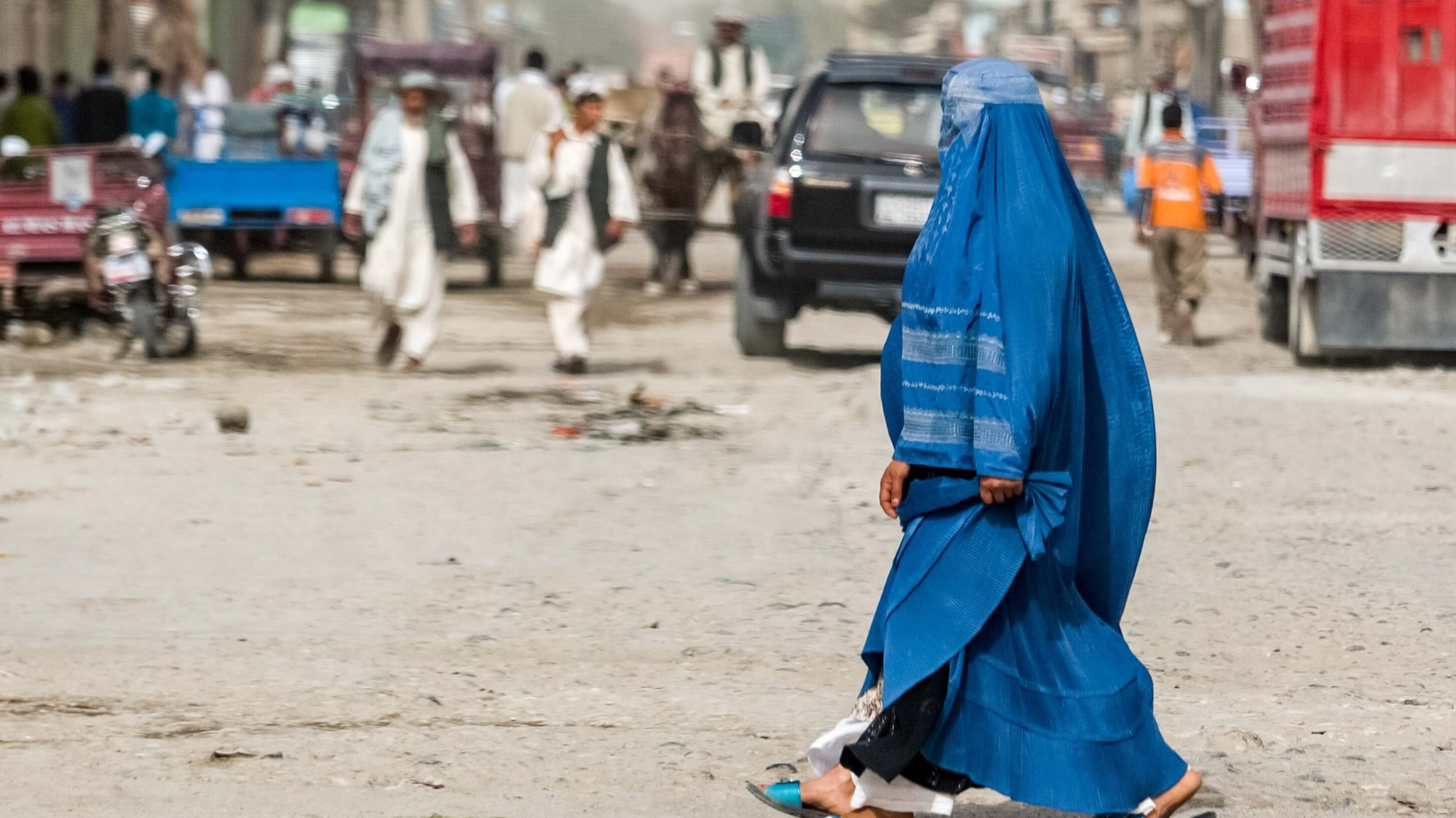 An Afghan woman in a burqa and locals are seen on the streets of Kabul. Photo: Shutterstock.
