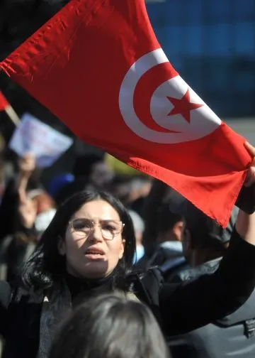 A woman raises the Tunisian flag during an Ennahda Party-led protest against the Tunisian president in Tunis, Tunisia on February 13, 2022. Photo: Mohamed Soufi.