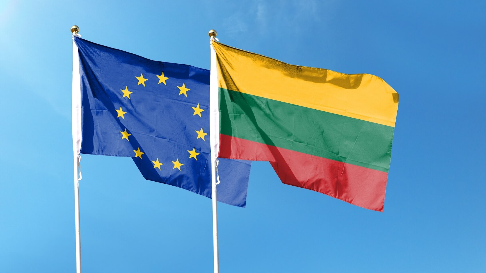 Lithuania and EU flags waving under a cloudy sky. Photo: Andy Liu.