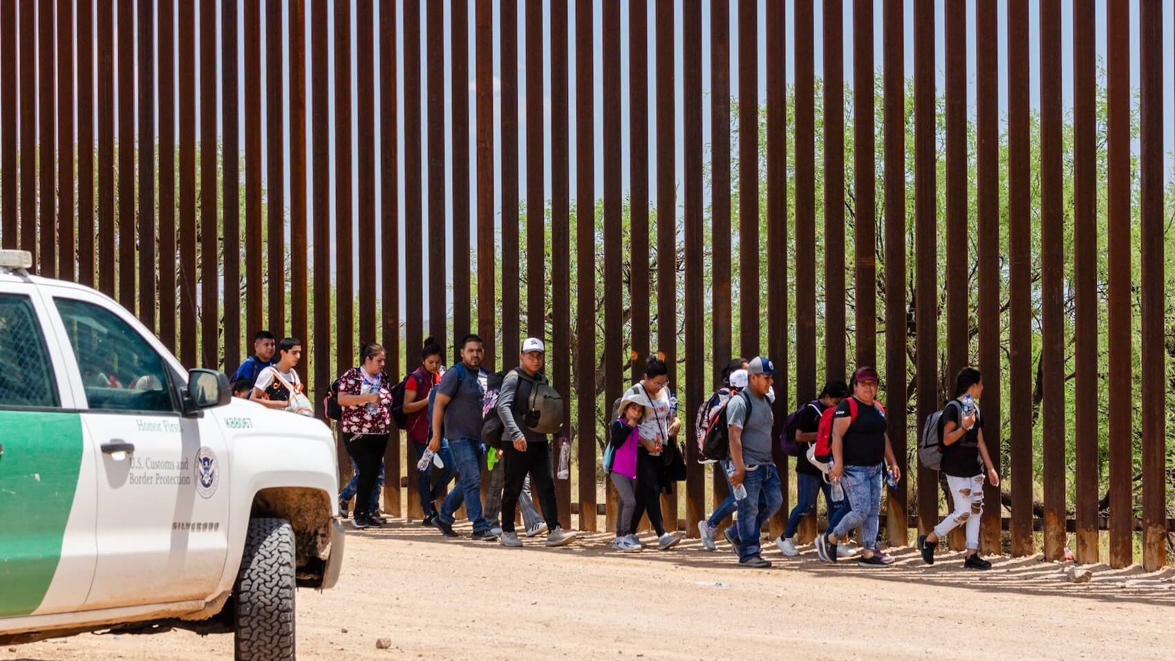 A group of migrants entered the U.S. from Mexico through an opening in the border fence near Sasabe, Arizona, and turned themselves in to a waiting CBP agent on July 15, 2023. Photo: Aaron Wells.