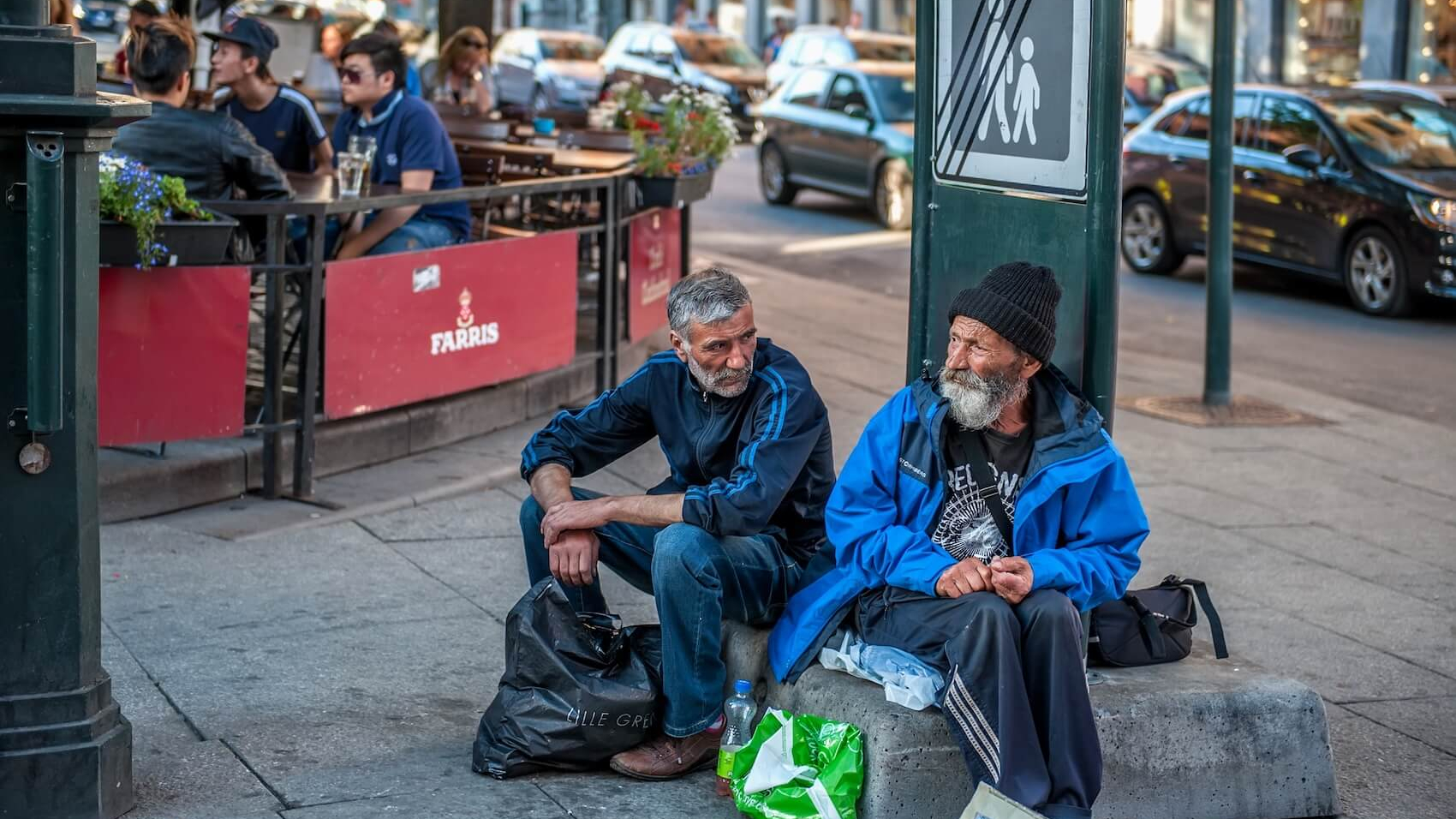 Two elderly men sit on the street in front of a café in Oslo, Norway, asking for alms on August 1, 2013. This image symbolizes the indifference of society and the state toward poverty. Photo: Medvedeva Oxana.