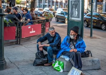 Two elderly men sit on the street in front of a café in Oslo, Norway, asking for alms on August 1, 2013. This image symbolizes the indifference of society and the state toward poverty. Photo: Medvedeva Oxana.