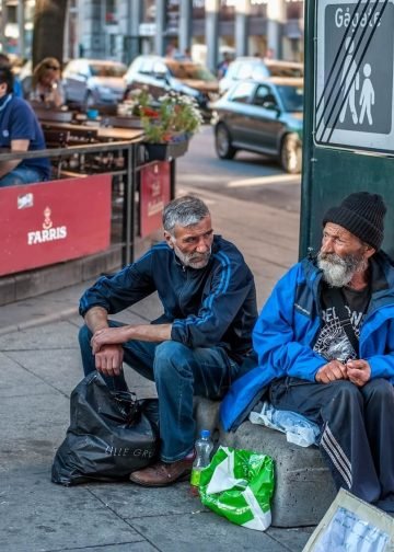 Two elderly men sit on the street in front of a café in Oslo, Norway, asking for alms on August 1, 2013. This image symbolizes the indifference of society and the state toward poverty. Photo: Medvedeva Oxana.