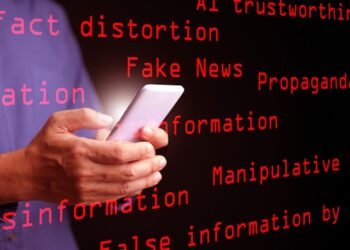 AI, artificial intelligence, and the concept of fake news, misinformation, and disinformation: A man uses his smartphone displaying the red text “Fake News,” surrounded by related keywords. Photo: Dreamstime.