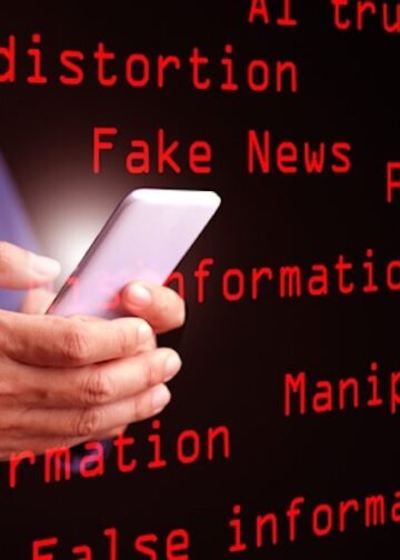 AI, artificial intelligence, and the concept of fake news, misinformation, and disinformation: A man uses his smartphone displaying the red text “Fake News,” surrounded by related keywords. Photo: Dreamstime.