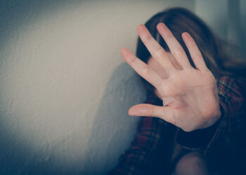 A survivor of domestic abuse sits in silence, reflecting the fear, trauma, and isolation experienced by countless women affected by violence, harassment, and exploitation. Photo: Dreamstime.