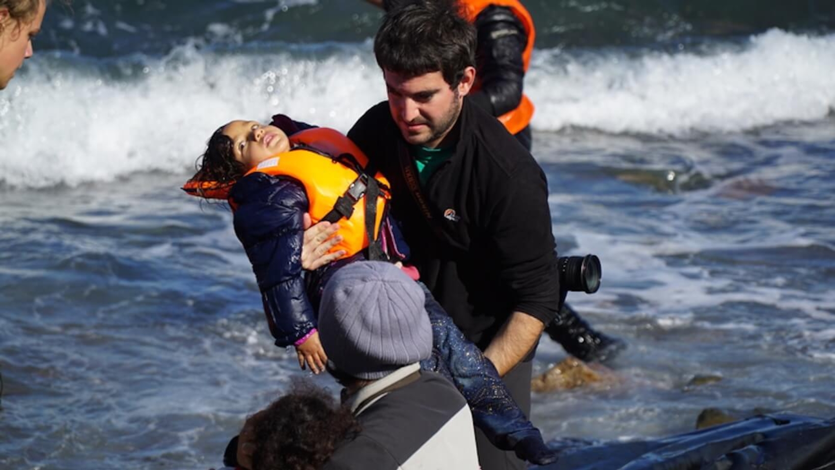 Refugee children are helped ashore after arriving by boat from Turkey on the Greek island of Lesbos, capturing a moment where relief and suffering coexist. Photo: Aleksandr Lutsenko.