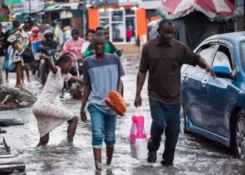 People walk along a flooded road after heavy rain in Lagos, Nigeria.